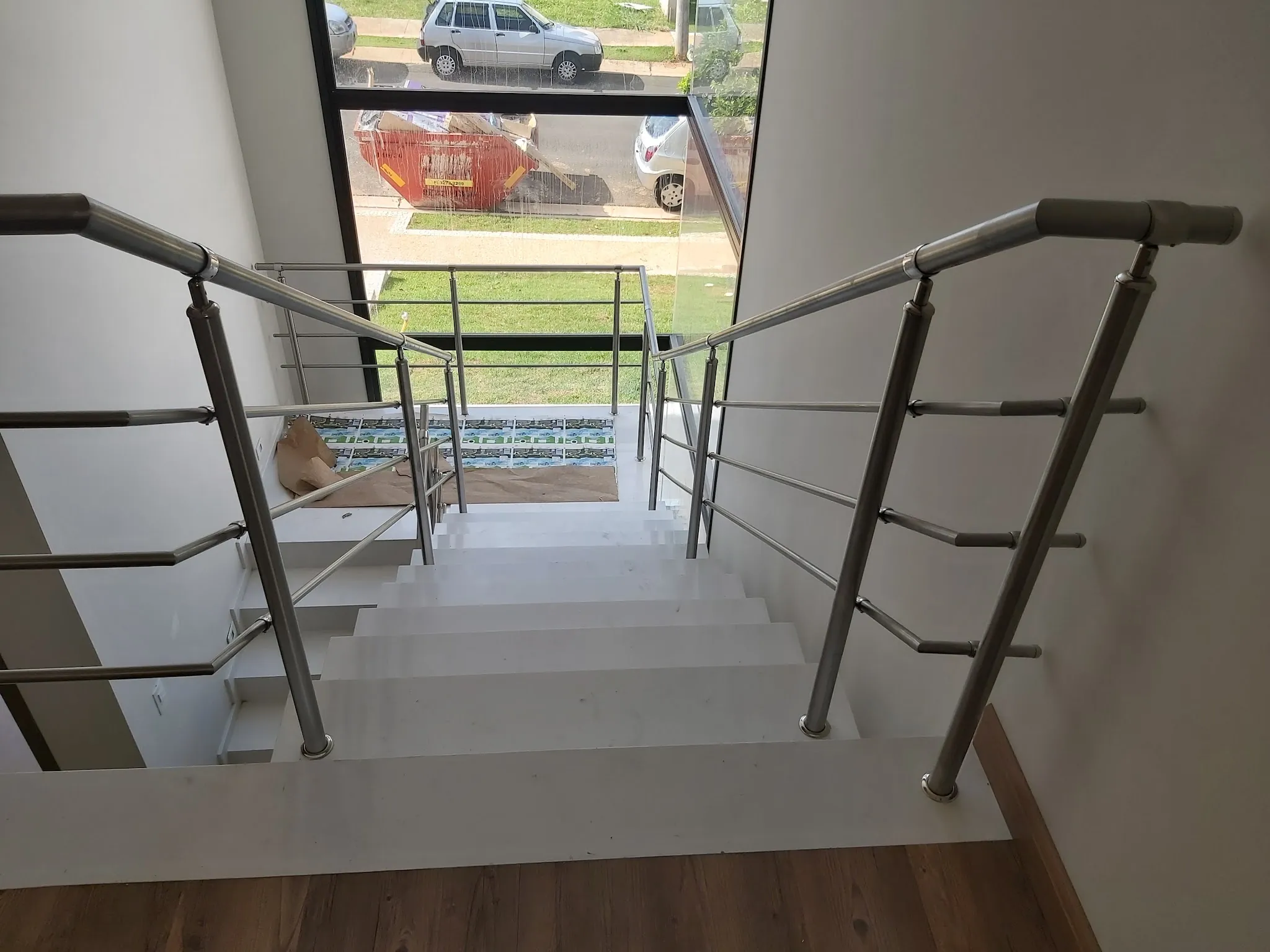 Escada com degraus de pedra clara, corrimão de inox e vista para a piscina